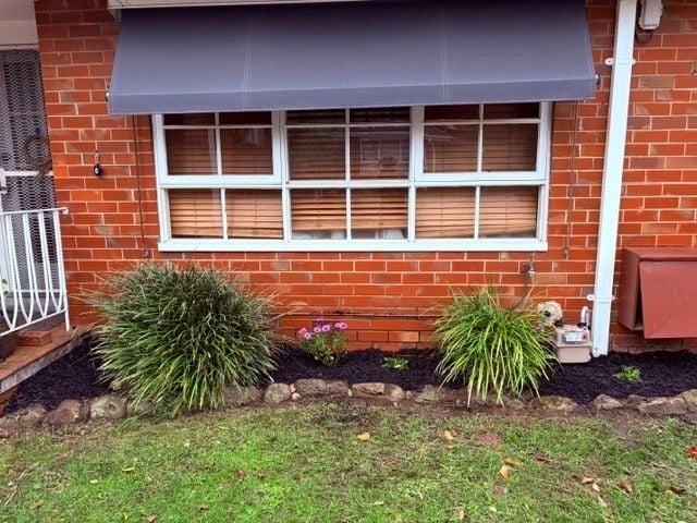Trimmed grasses and mulched garden bed in front of a brick home
