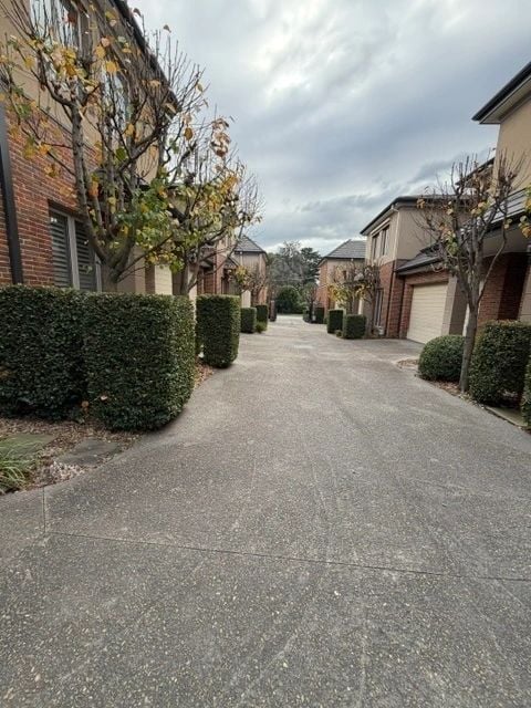Row of precision-trimmed hedges along a townhouse driveway
