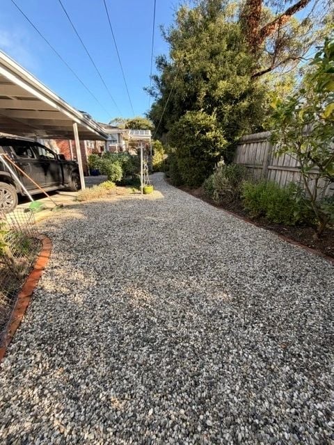 Pebble driveway cleared of weeds beside a tidy garden strip